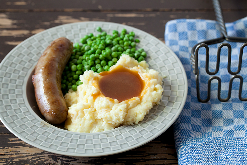 Aardappelpuree met jus, groenten en een worstje